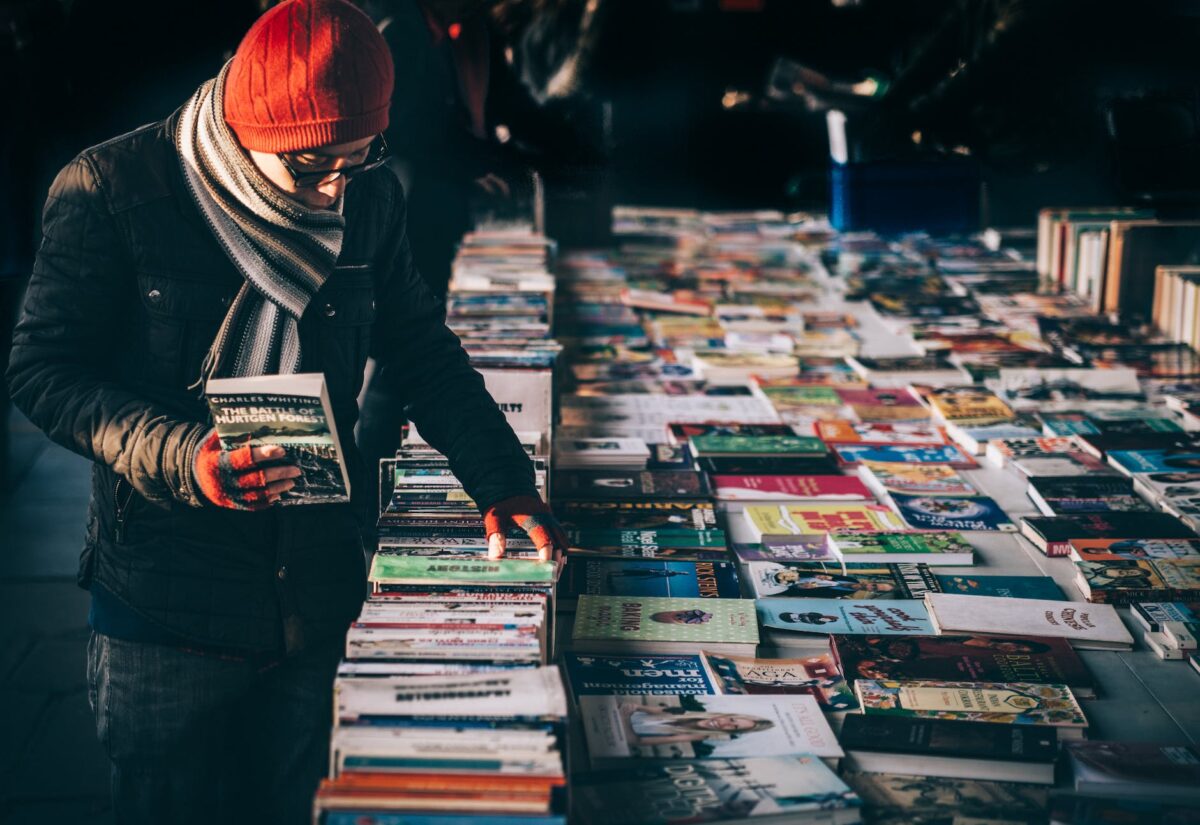 person holding book while browsing on book lot