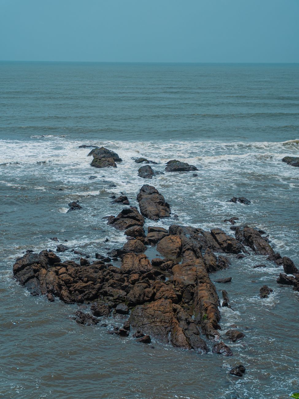 rocky shoreline with waves under clear blue sky